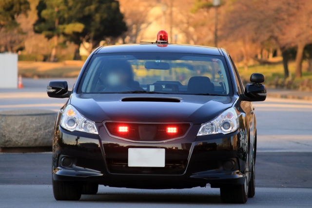 覆面パトカーが赤色灯を点灯させて停車している様子